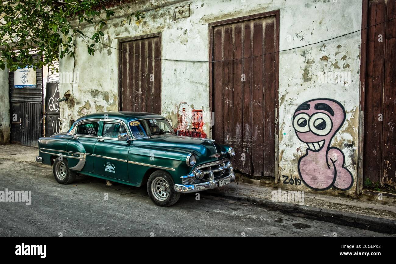 Havana, Cuba, July 2019, green American 50`s-60`s Chevrolet car parked by graffiti in the oldest part of the city Stock Photo